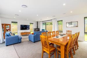 a living room with a wooden table and blue chairs at Elegant, Executive Retreat in Methven