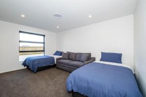 1 dormitorio con 2 camas, sofá y ventana en Elegant, Executive Retreat en Methven