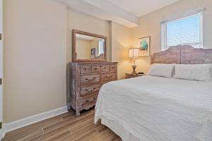 a bedroom with a bed and a dresser with a mirror at Island Royale 404 in Gulf Shores