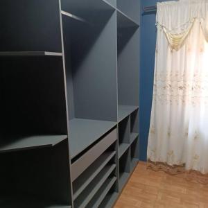 uma estante de livros cinzenta num quarto com uma cortina em Gray House 4 Londrina - Pr (Jd. Santiago) em Londrina