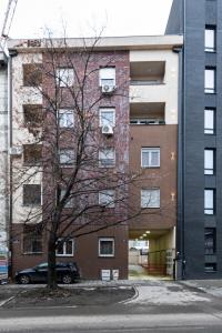 a tall building with a tree in front of it at !PROMO! Giallo Modern Studio-Free Private Parking-Fast WI-FI in Novi Sad