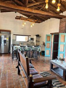 Casa Castañeto Barichara في باريكارا: غرفة معيشة مع طاولات وكراسي ومطبخ