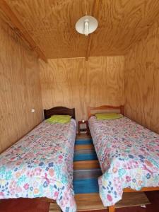 2 camas en una habitación con paredes de madera en cabaña hermosa vista en maicolpue playa grande, en Osorno