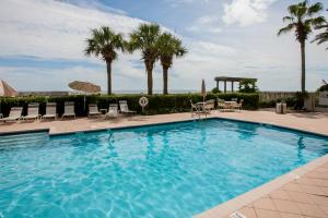 a large swimming pool with chairs and palm trees at Beach Club C-102 in Gulf Shores +42 photos