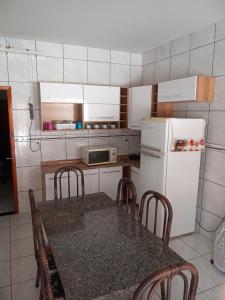 uma cozinha com uma mesa com cadeiras e um frigorífico em Recanto WL em Olímpia