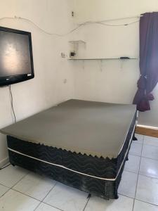 a bed in a room next to a tv at Kitinete Aconchegante in Porto De Galinhas