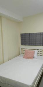 um quarto com uma grande cama branca e uma almofada rosa em Studio Guest Suite Near The New EVRMC Hospital & San Juanico Bridge Tacloban City, Leyte, Philippines em Tacloban