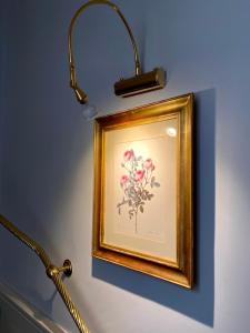 a light on a wall with a picture of flowers at Lilium Boutique Hotel in Rome