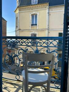una sedia bianca seduta su un balcone con un edificio di Grande maison de pêcheur - centre de Trouville a Trouville-sur-Mer