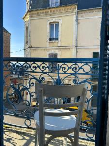 une chaise blanche assise sur un balcon avec un bâtiment dans l'établissement Grande maison de pêcheur - centre de Trouville, à Trouville-sur-Mer