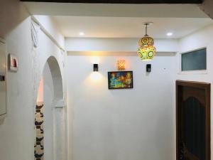 a hallway with a chandelier and a white wall at Ali Baba Hostel in Jaipur