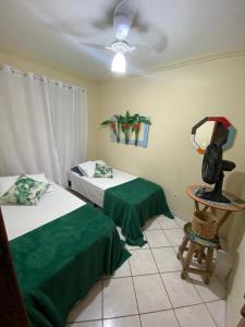 a bedroom with two beds and a chair and a fan at Quarto Ponta Negra in Angra dos Reis