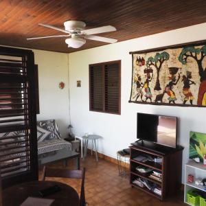 a living room with a ceiling fan and a tv at Villa Vivi in Gros-Morne