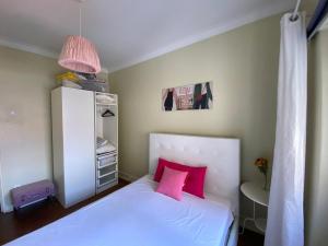 een slaapkamer met een wit bed met roze kussens bij EVD-RENTALS OLIVAL BASTOS in Lissabon