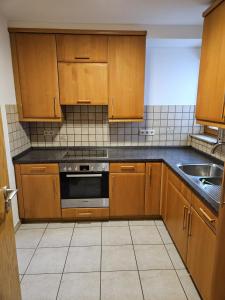 a kitchen with wooden cabinets and a stove and a sink at Einfaches ruhiges Apartment in Laichingen