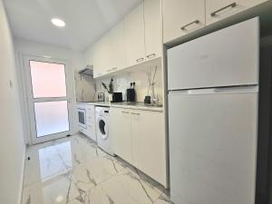 een witte keuken met een koelkast en een raam bij 1BD Beach Apartment in Paphos City
