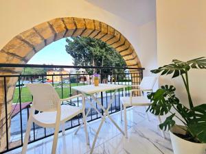 een tafel en stoelen op een balkon met een boog bij 1BD Beach Apartment in Paphos City