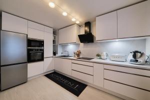una cocina con armarios blancos y electrodomésticos negros en Appartement parisien au cœur de Montparnasse, en París