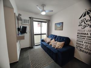 een woonkamer met een blauwe bank en een tv bij Enseada Guarujá Ap214 in Guarujá