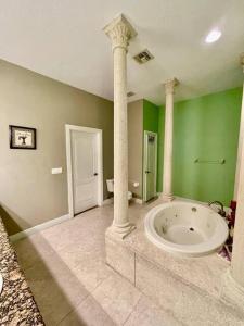 a large bathroom with a large tub and columns at King Suite & Jacuzzi Luxe Getaway in Port St Lucie in Port Saint Lucie