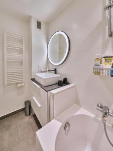 W białej łazience znajduje się umywalka i lustro. w obiekcie Appartement parisien au cœur de Montparnasse w Paryżu