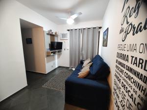 een woonkamer met een blauwe bank voor een muur bij Enseada Guarujá Ap214 in Guarujá