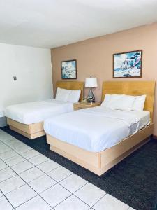 2 bedden in een hotelkamer met witte lakens bij Tides Inn at Stehli Beach in Locust Valley
