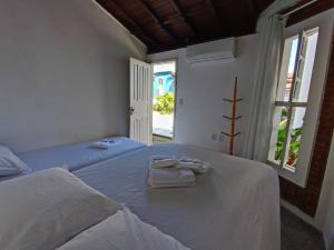 a bedroom with two beds with towels on them at Na Casa da Santa Hostel & Bistrô - Tudo a pé - 100 mt da Passarela do Álcool in Porto Seguro