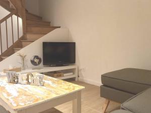 a living room with a table with a tv and stairs at Maison chaleureuse idéalement située 