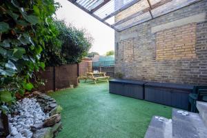 a garden with a patio with green grass at BIG House close to Metro Underground - Sleeps up to 13 in London