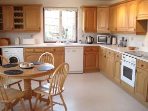 a kitchen with wooden cabinets and a table with chairs at Church Meadow in Golant