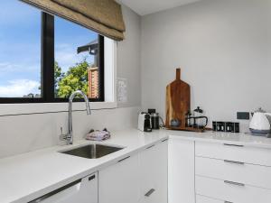 Una cocina blanca con fregadero y ventana. en Lake Taupō Luxury Home plus Hideaway Apartment, en Taupo 31 fotos más