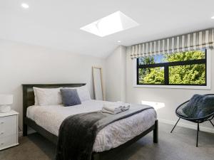Un dormitorio con una cama y una ventana y una silla. en Lake Taupō Luxury Home plus Hideaway Apartment, en Taupo