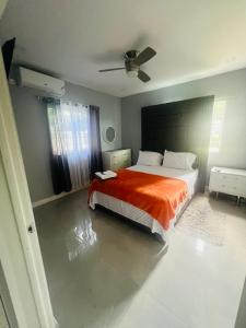 a bedroom with a bed with an orange blanket at Large Contemporary Two Bedroom in Kingston