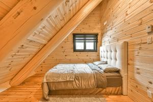 ein Schlafzimmer mit einem Bett in einem Holzzimmer in der Unterkunft Le Chalet Enchanté in Saint-Donat-de-Montcalm