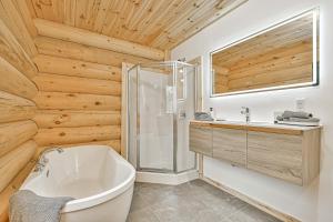 a bathroom with a white tub and wooden walls at Le Chalet Enchanté in Saint-Donat-de-Montcalm