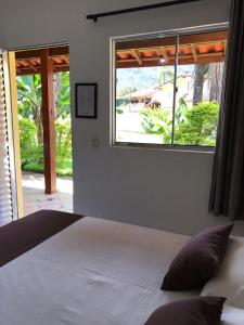a bedroom with a large bed and a window at Pousada Ana e o Mar in Ubatuba