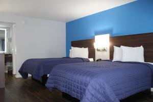 2 camas en una habitación de hotel con paredes azules en Knights Inn St. George, en Saint George