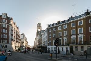 eine Stadtstraße mit Gebäuden und einem Uhrturm in der Unterkunft Regent's Park & Baker Street Modern Apartments! in London