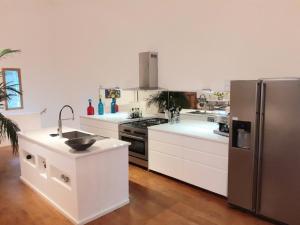 a kitchen with white cabinets and a stainless steel refrigerator at LUXURY 270M² HOUSE OF CHARACTER IN OLD STONES WITH HEATED POOL, NEAR CALVI in Calenzana