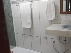 a white bathroom with a sink and a mirror at Aconchegante casa de Temporada em Búzios. in Armacao dos Buzios