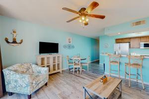 a living room with a ceiling fan and a kitchen at Destin West Pelican #501 in Fort Walton Beach