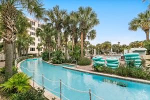 a swimming pool with blue chairs and palm trees at Destin West Pelican #501 in Fort Walton Beach