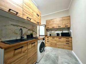 a kitchen with wooden cabinets and a washing machine at MMRent Warmly Room in Gdańsk