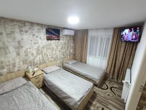 a room with two beds and a tv on the wall at Casa Bianca Pensiune in Târgu Jiu