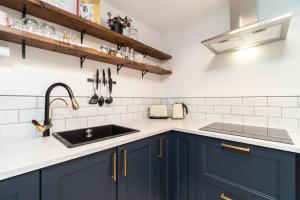 una cocina con armarios azules y fregadero en Stylish City Pad with Free Private Parking en Glasgow