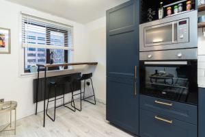 cocina con armario azul y microondas en Stylish City Pad with Free Private Parking, en Glasgow