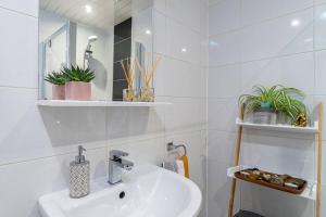 uma casa de banho branca com um lavatório e um espelho em Stylish City Pad with Free Private Parking em Glasgow