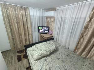 Schlafzimmer mit einem Bett, einem TV und Vorhängen in der Unterkunft Casa Bianca Pensiune in Târgu Jiu