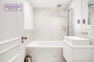 a white bathroom with a tub and a sink at Premium 1 Bed 1 Bath Apartments For Corporates By REDWOOD STAYS in Reading
